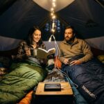 A couple using low-wattage USB camping lights powered by a compact power bank in a tent.
